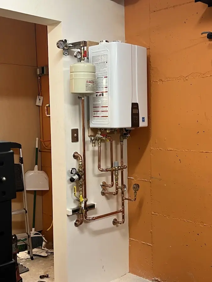 Plumbing technician inspecting water heater connections in Bedminster
